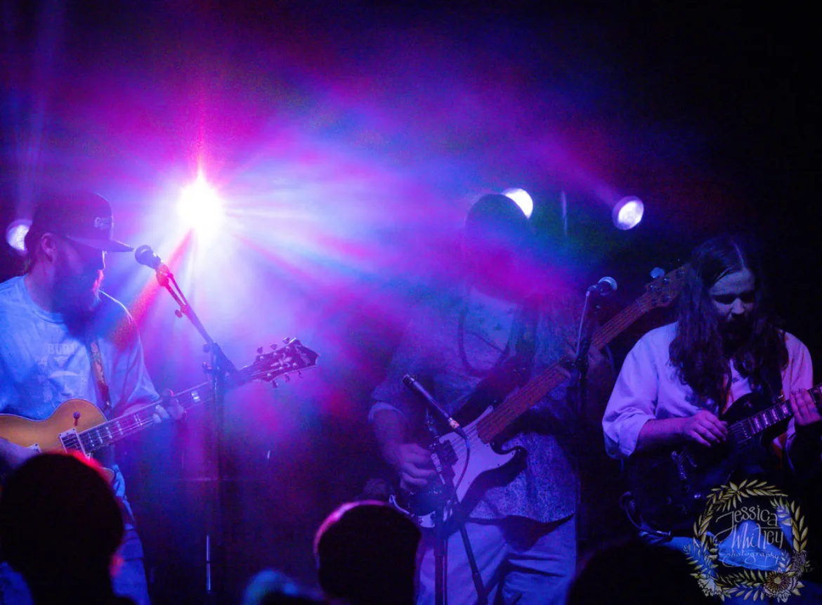 Performers on stage at a live outdoor event produced for a large audience